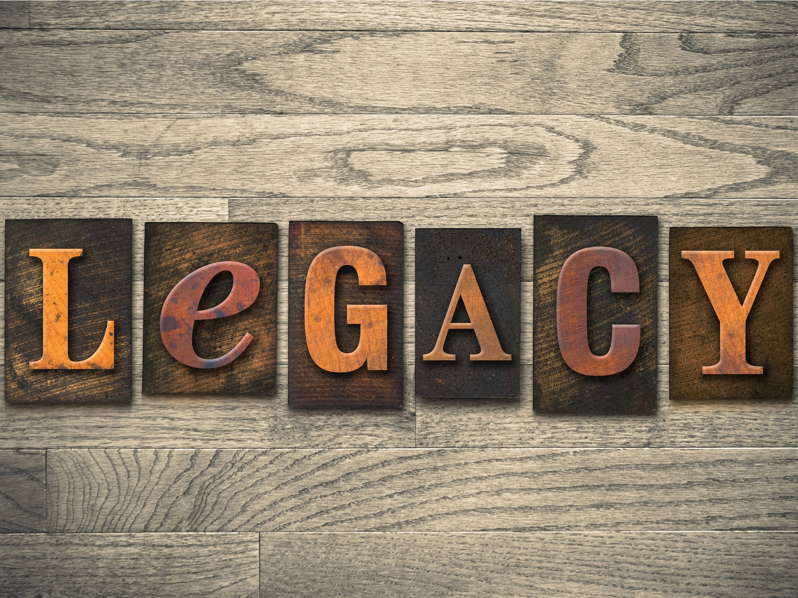 Wooden letterpress blocks spelling the word Legacy on a wood grain background, symbolizing heritage, craftsmanship, and lasting impact in business and culture.
